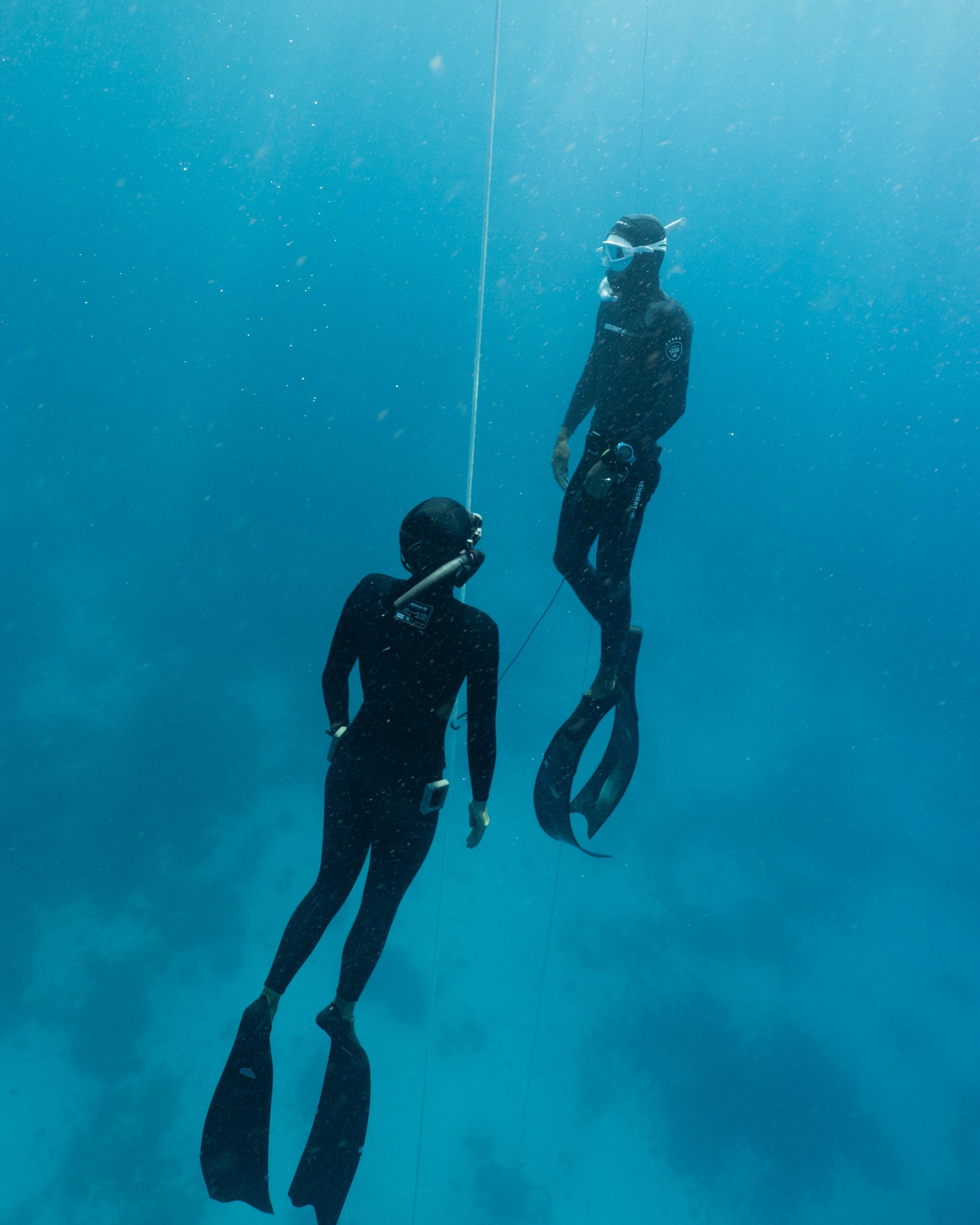 Two freedivers are diving on the training line, one is doing the safety as the other diver is ascending.